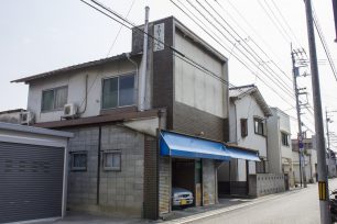 仏生山のお成り街道沿いにある店舗跡。壁の上部に残る看板と、青いテントが営業当時の名残です。